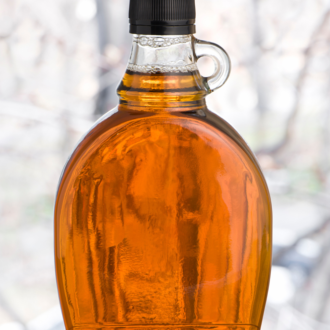 a single glass jar of maple syrup in front of a winter background
